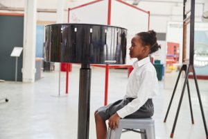 Schoolgirl sitting in front of zoetrope at a science centre