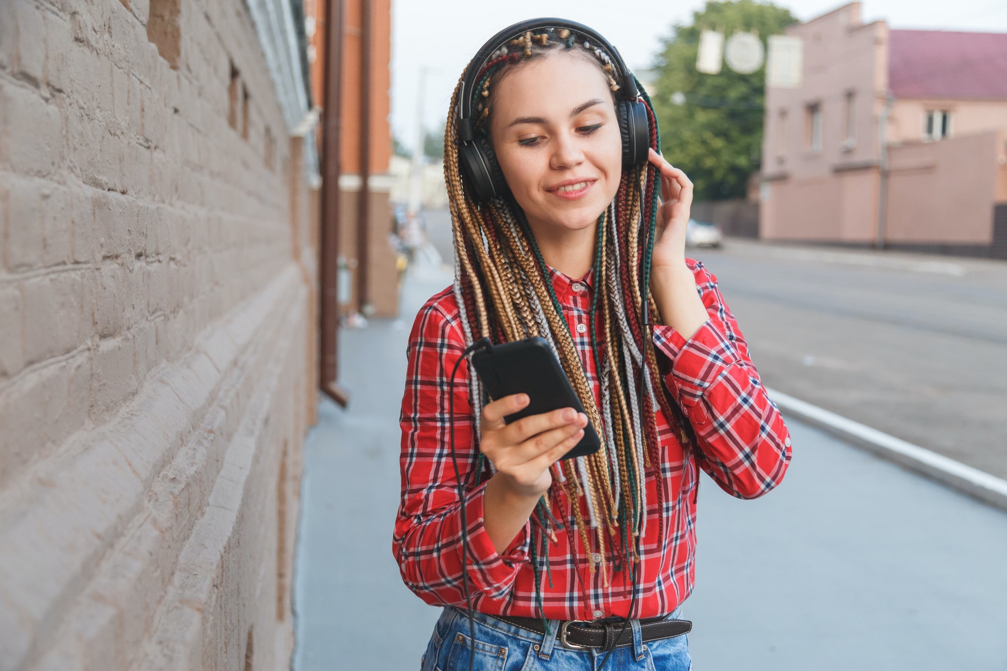 Young woman with colored pigtails listening to music in headphones on the street