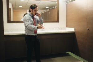 Furious Business Man Screaming On Cell Phone In Office Restroom