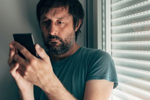 Man text messaging on mobile phone in privacy of bedroom