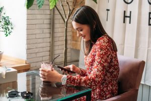 Online dating, Love at distance. Woman in cafe using dating app and swiping user photos. Young woman