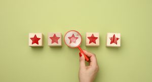 Five red stars and a hand with a plastic magnifier on a green background