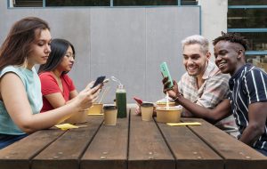 group of friends using smart phone, sharing funny photo or video content in social networks